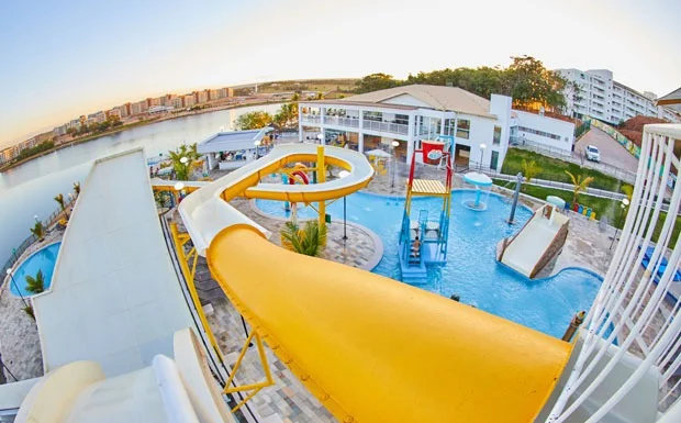Piscina de borda infinita com vista para o lago ao entardecer.