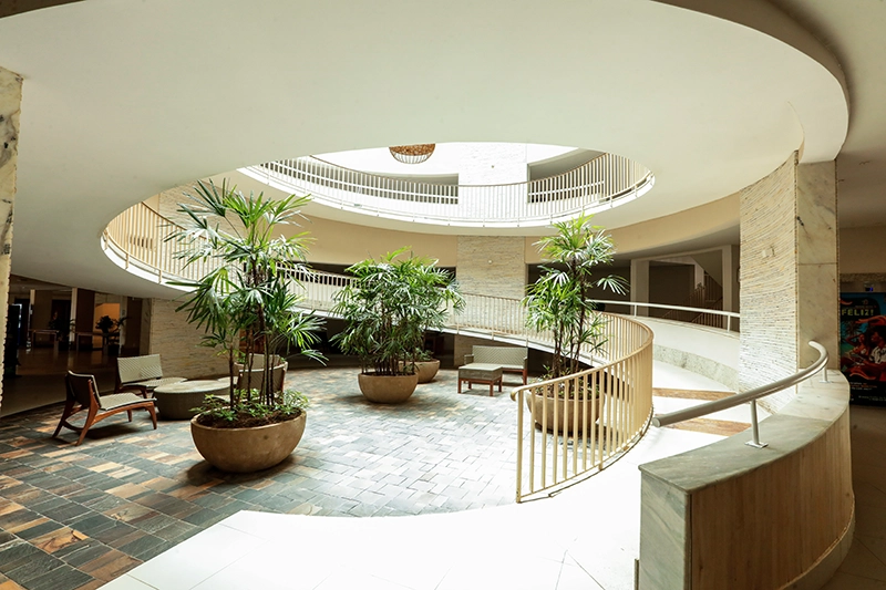Lobby do hotel com arquitetura em formato circular e plantas.