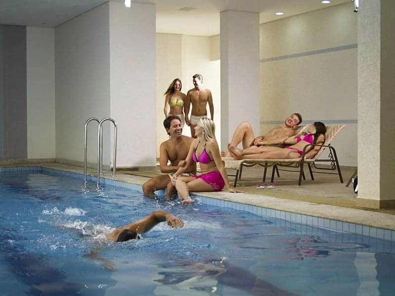 Área de piscina com toboágua e coqueiros ao redor.