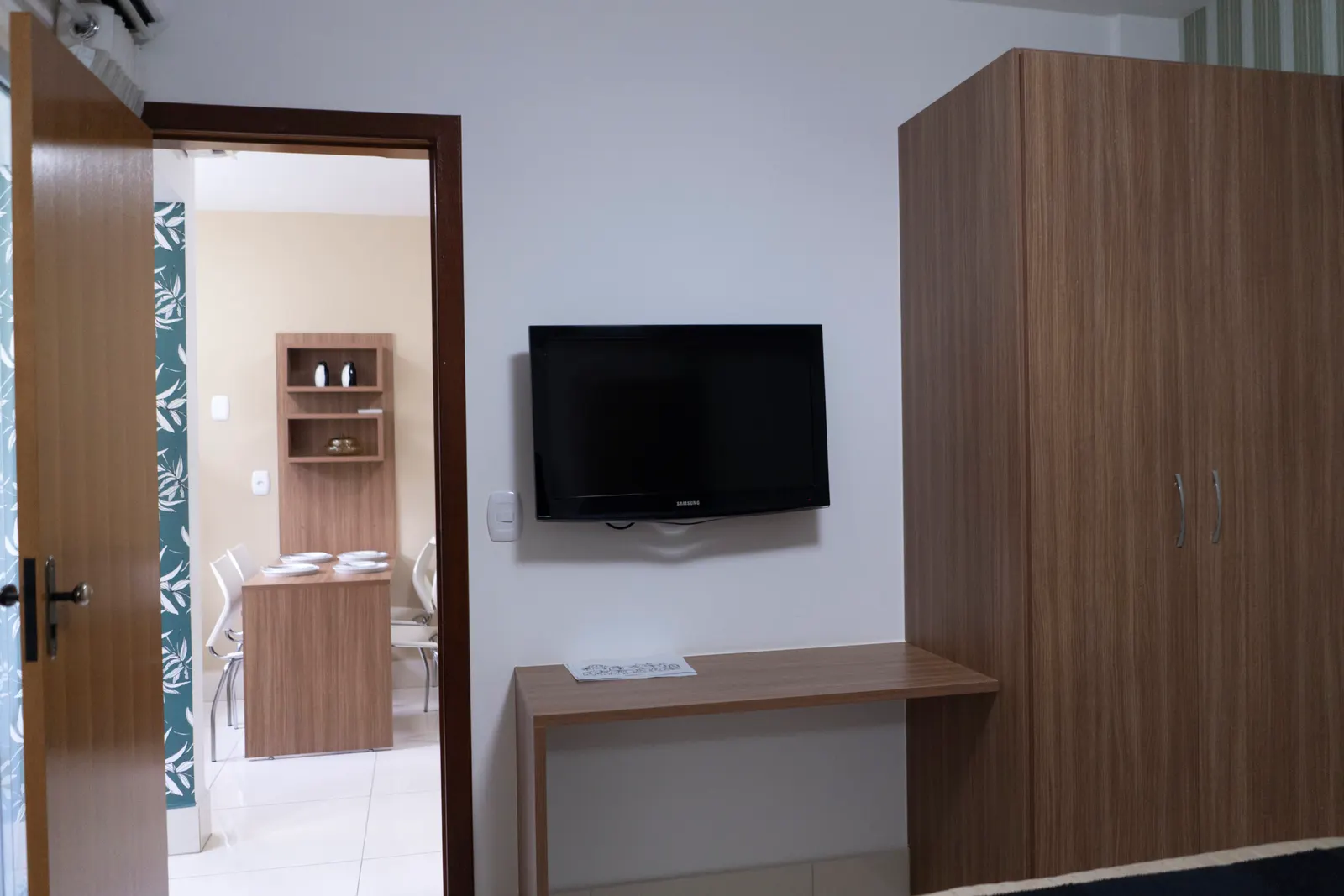 Ambiente do apartamento com TV, bancada e guarda-roupa.