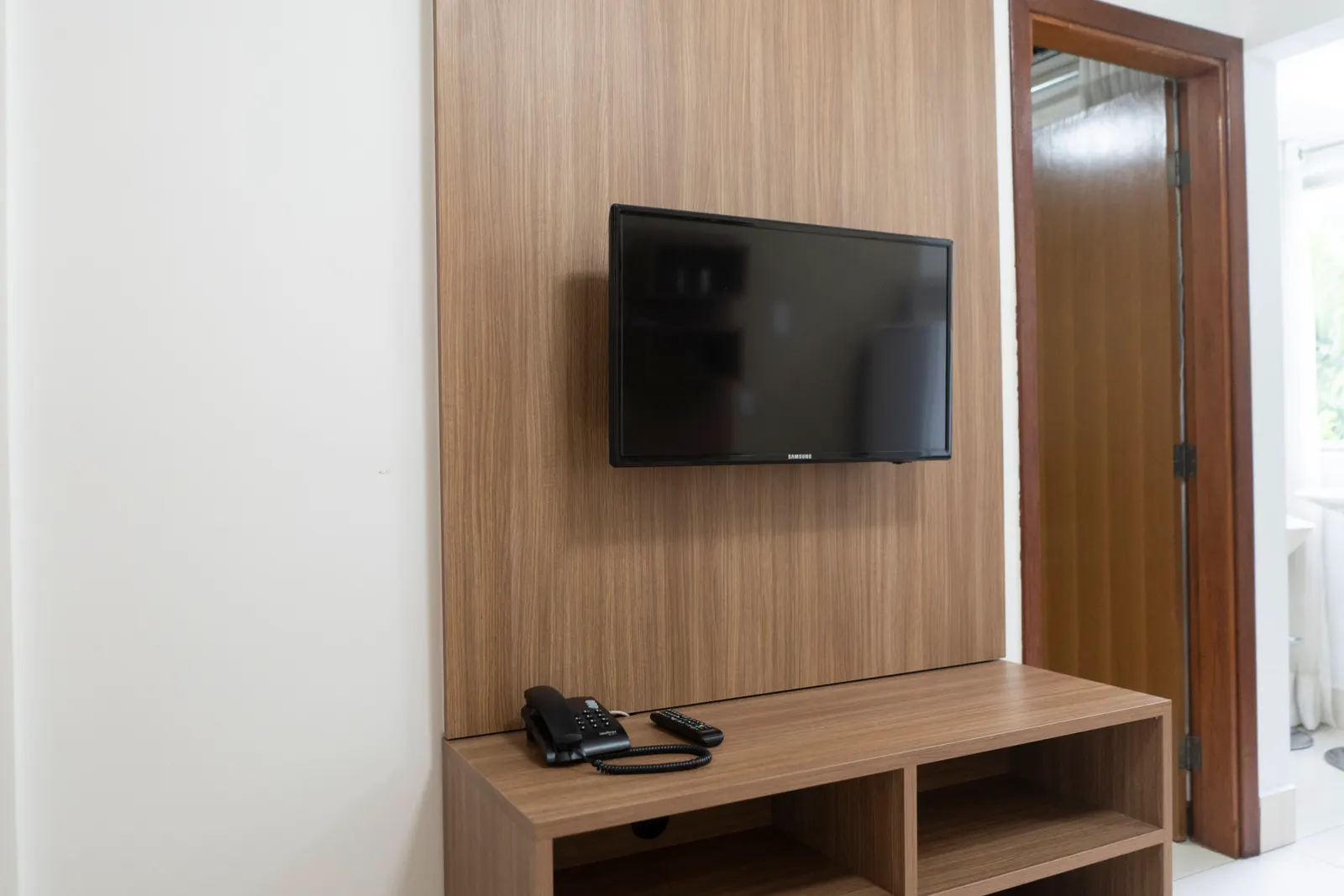 Sala do apartamento com painel de madeira e TV.