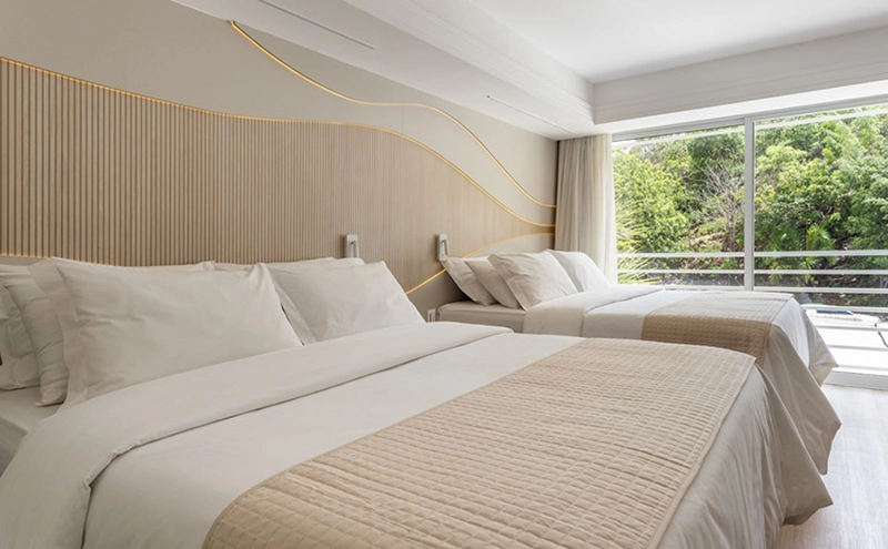 Quarto de casal com cama arrumada e acesso à varanda com vista.