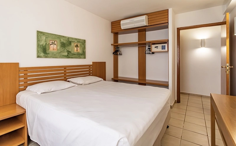 Quarto com cama de casal embutida em móvel de madeira.