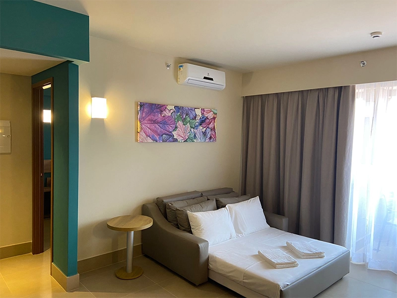 Sala de um apartamento com sofá-cama e vista para a janela.