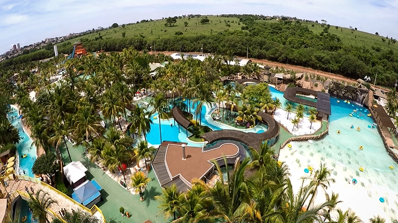 Vista aérea de uma piscina de formato irregular cercada por vegetação exuberante.