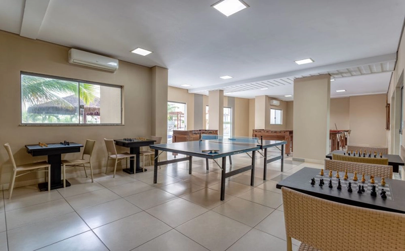 Cafeteria ou área de alimentação do hotel com mesas e balcão ao fundo.