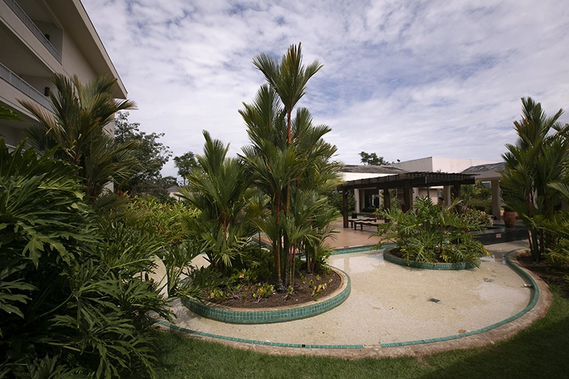Jardim interno do resort com paisagismo e um pequeno caminho.