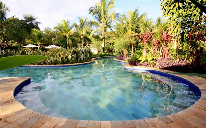 Piscina com área de deck molhado e espreguiçadeiras dentro d'água.