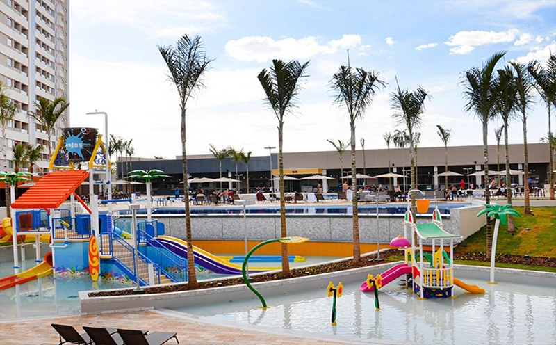 Playground externo com brinquedos e gramado sintético.