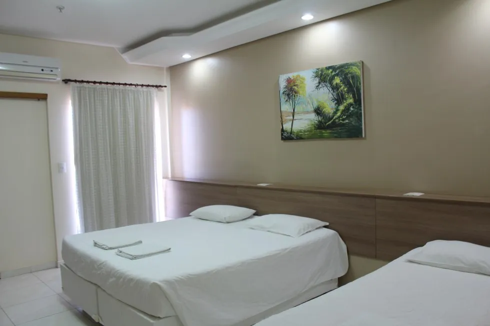 Quarto com duas camas de solteiro, ar-condicionado e decoração aconchegante.