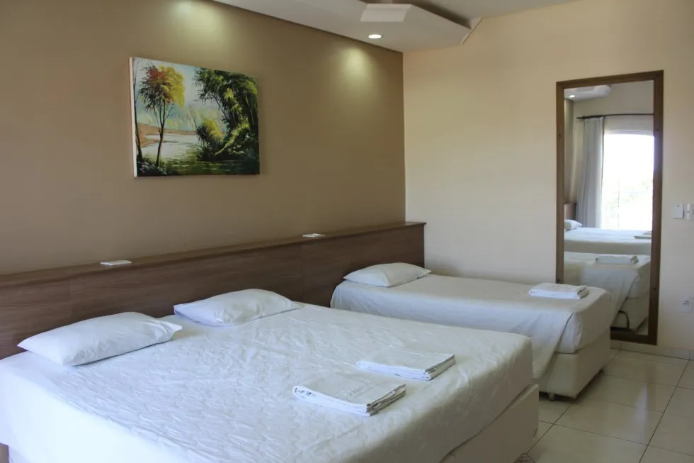 Quarto de casal com espelho de corpo inteiro e quadro decorativo.