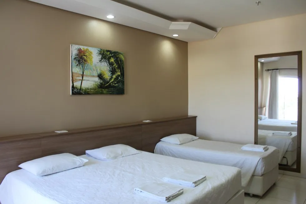 Quarto com painel de madeira na cabeceira e iluminação embutida.