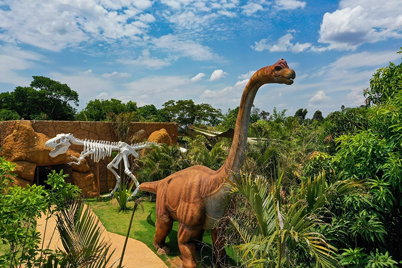 Réplica de dinossauro saurópode em meio à vegetação do Vale dos Dinossauros